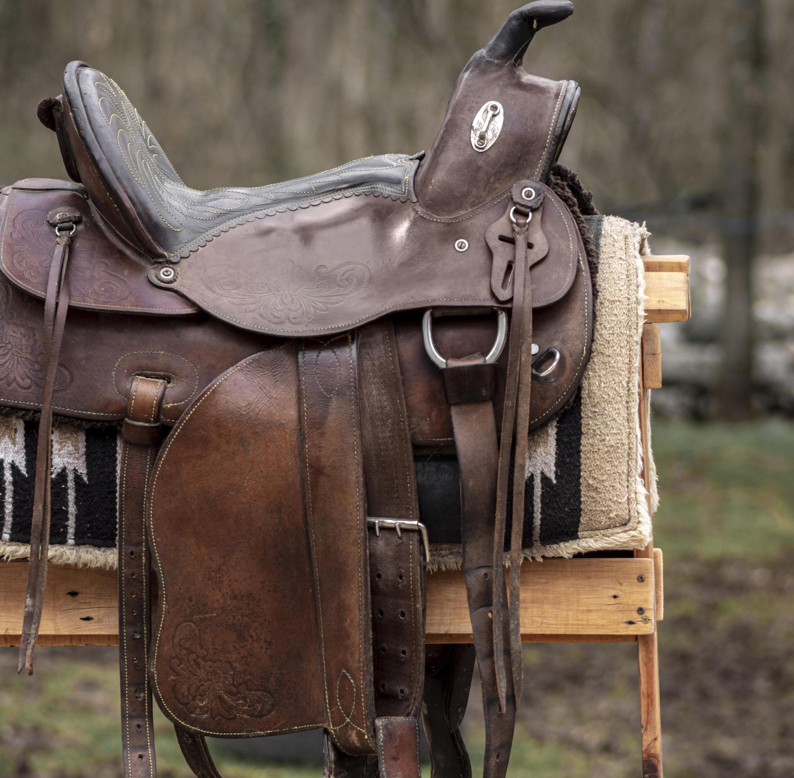 Vegetable tanned leather western saddle on a wooden rail